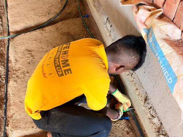 Porous pipe being laid along a foundation trench for pre-construction termite treatment